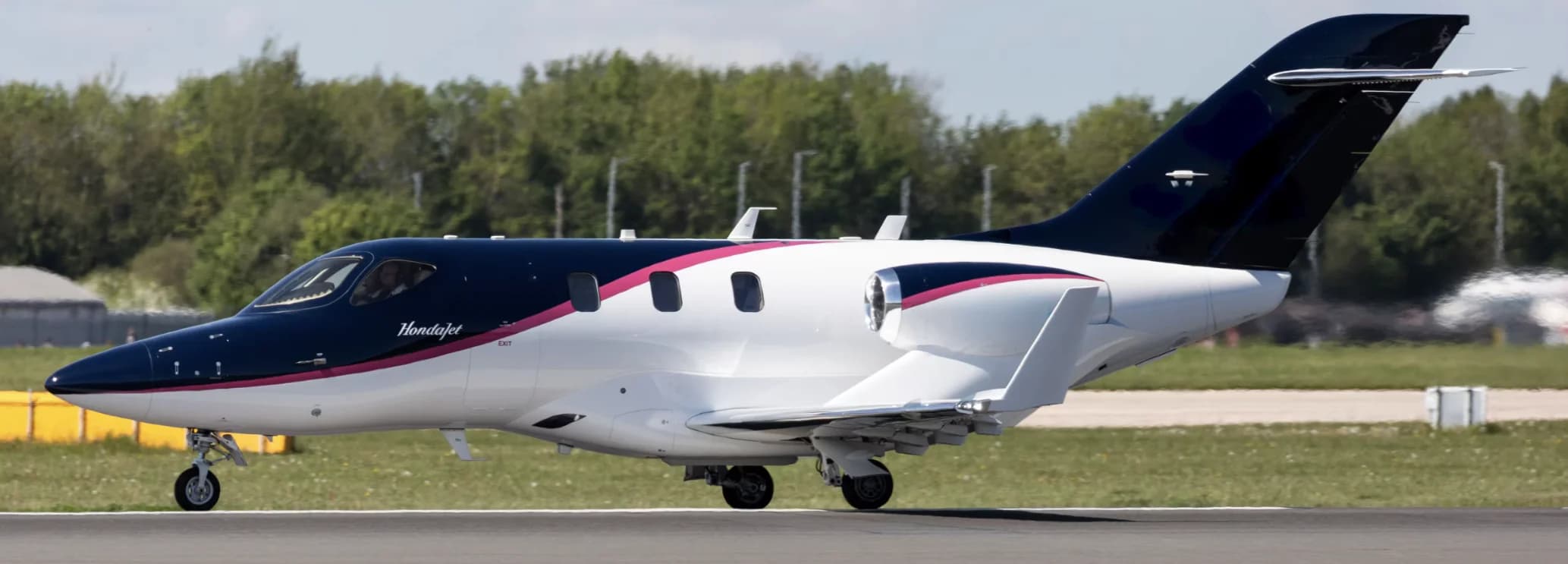 HondaJet Elite II very light jet charter with distinctive over-the-wing engines, white fuselage with blue accent stripe, in cruise flight