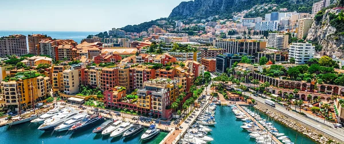 Daytime view of the ornate Monte Carlo Opera House architecture with the dramatic mountain and coastal backdrop in Monaco.