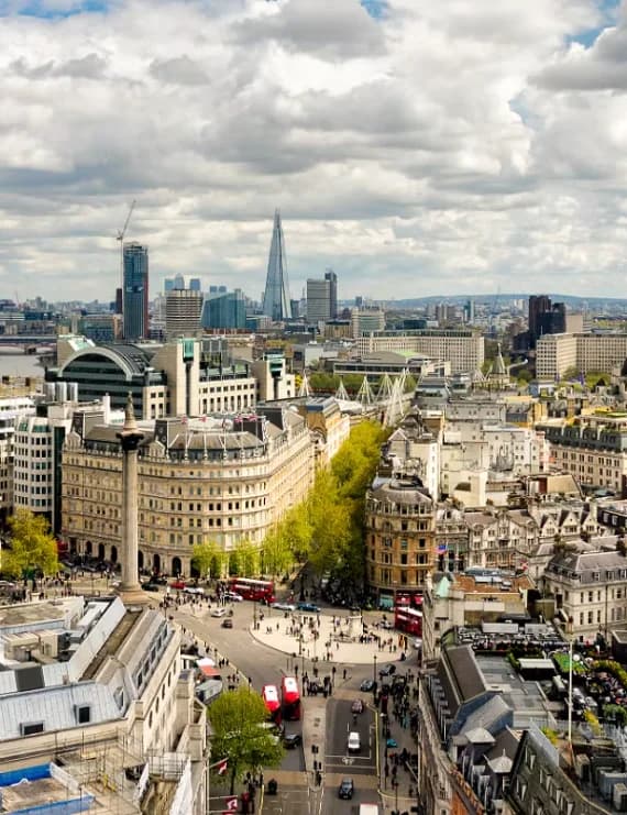 High-angle panoramic view of London's skyline including the Shard, London Eye, and Trafalgar Square under a cloudy sky in the United Kingdom.