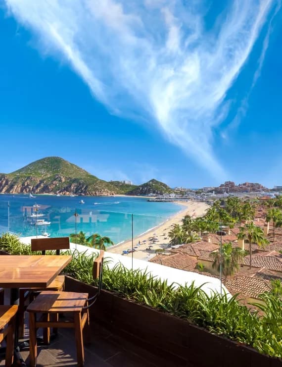 Luxury resort outdoor dining terrace overlooking Medano Beach and the Bay of Cabo San Lucas.