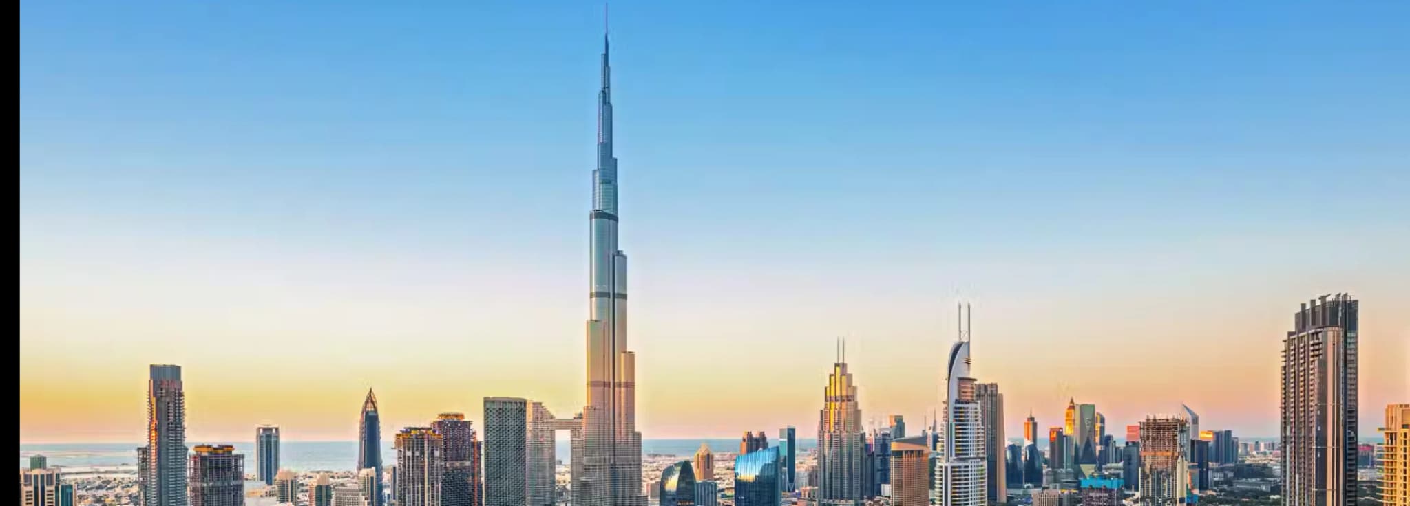 Standard: High-angle sunset view over Downtown Dubai featuring the Burj Khalifa, the Dubai Fountain lake, and the modern city skyline.