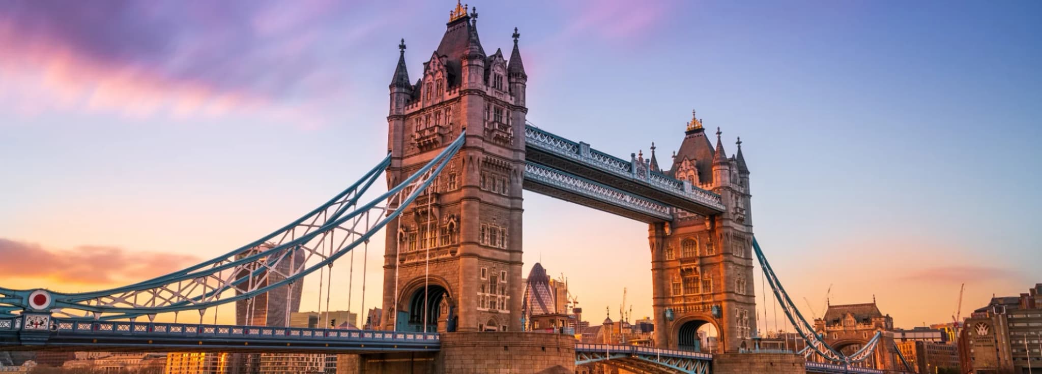 Majestic view of Tower Bridge spanning the River Thames against a colorful sunset sky in London, England.