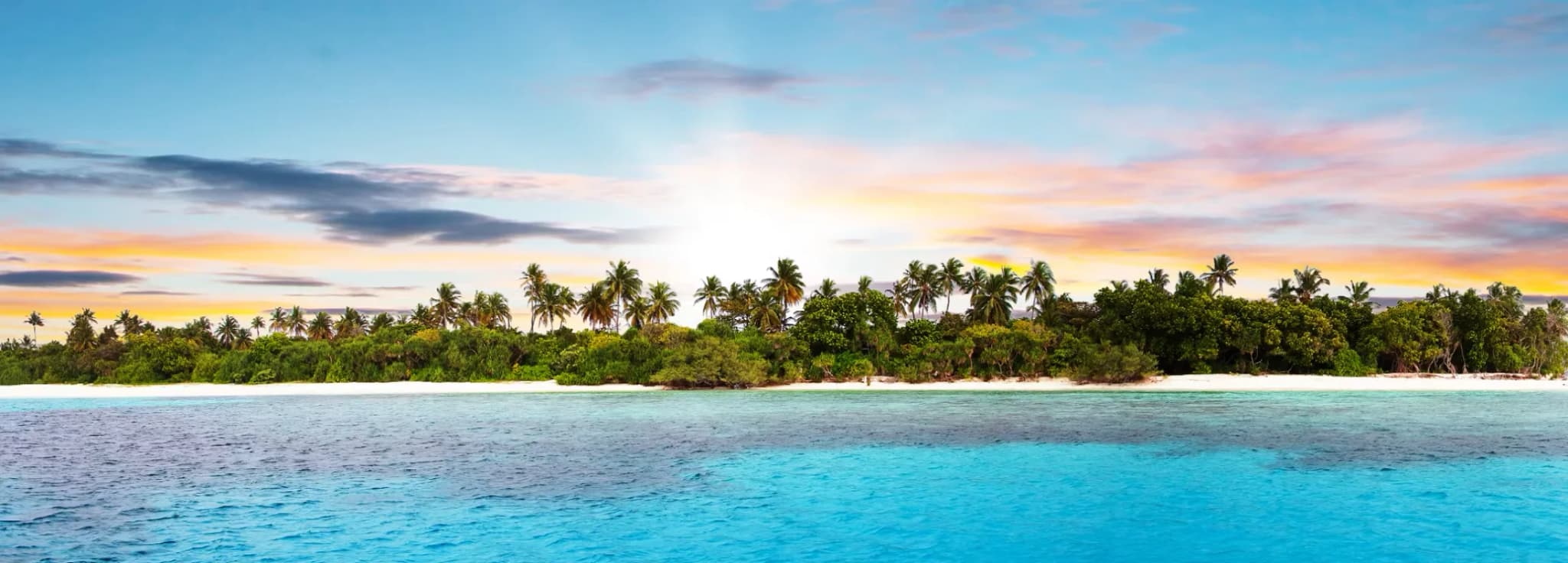 Panoramic view of a lush tropical private island at sunset in the Caribbean Sea.