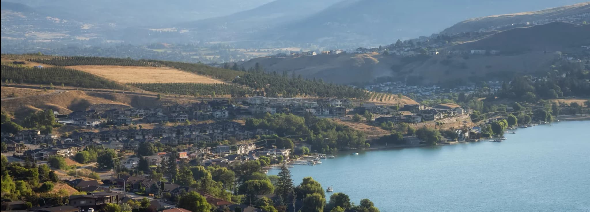 Aerial view of lakefront homes and rolling hills in Vernon BC, near Vernon Regional Airport.