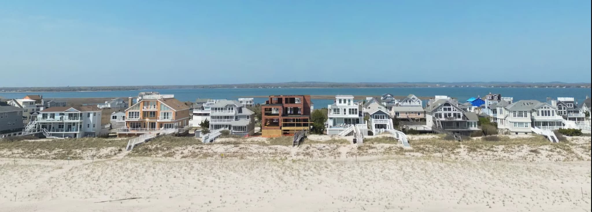 Row of luxury beach homes built along sandy ocean dunes facing the bay on Long Island South Fork