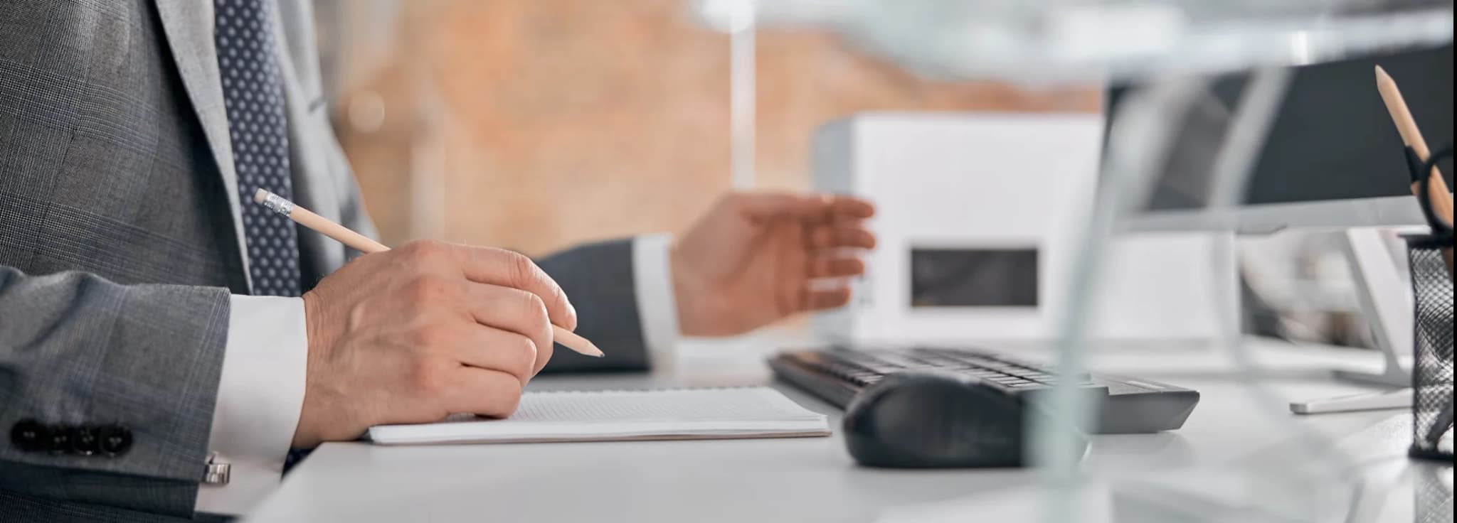 Business professional reviewing flight itineraries and making notes at a desk in an office environment.