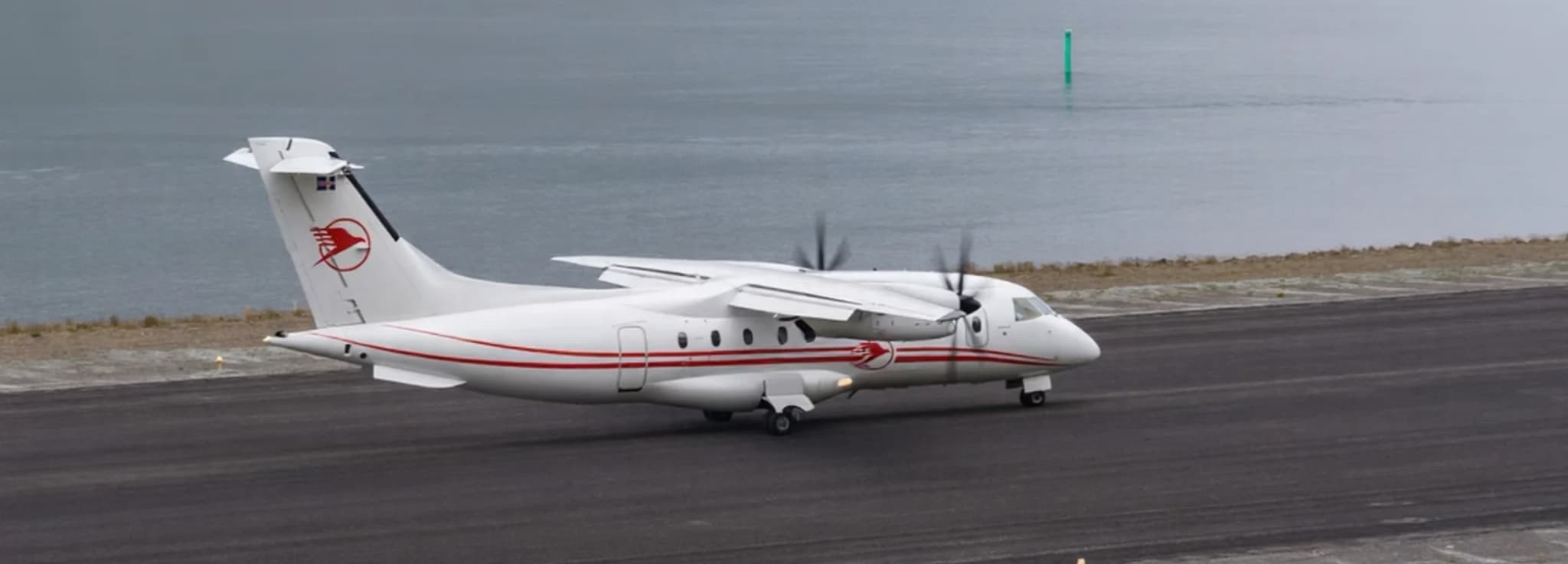 Dornier 328 twin-engine turboprop regional airliner taxiing on a coastal airport runway.