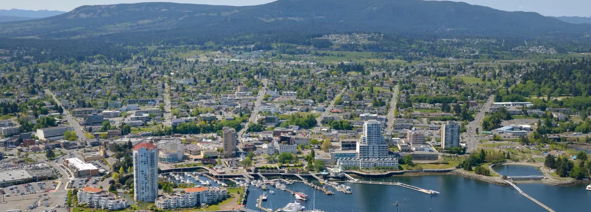 High aerial view of downtown Nanaimo waterfront, harbor marina, high-rise buildings, and Mount Benson