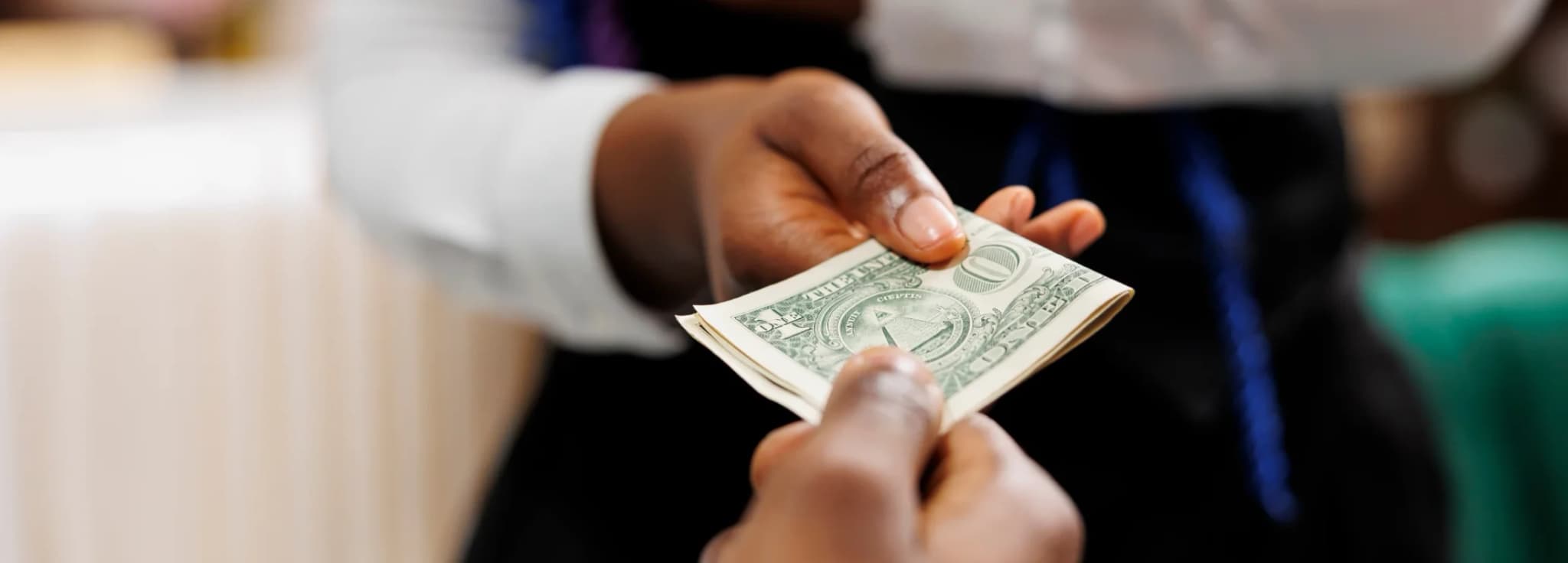 Close-up of hands exchanging currency notes during a financial transaction for travel or charter costs.